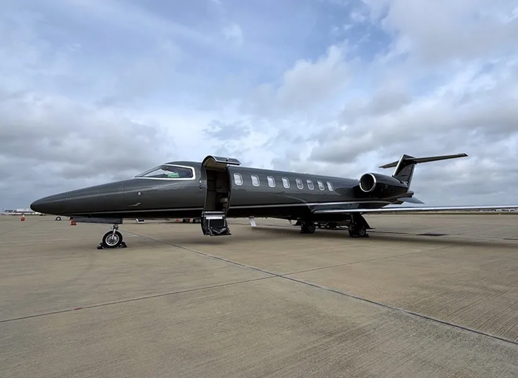 Black 2002 Learjet 45 N454MF parked on an airport apron with the cabin door open
