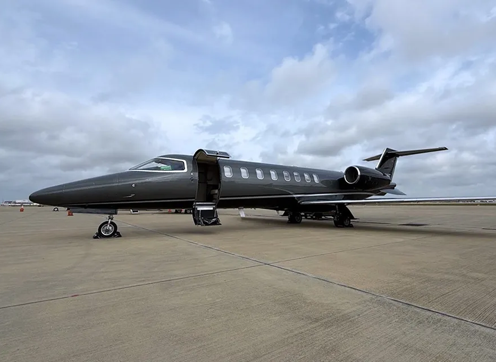 Black 2002 Learjet 45 N454MF parked on an airport apron with the cabin door open