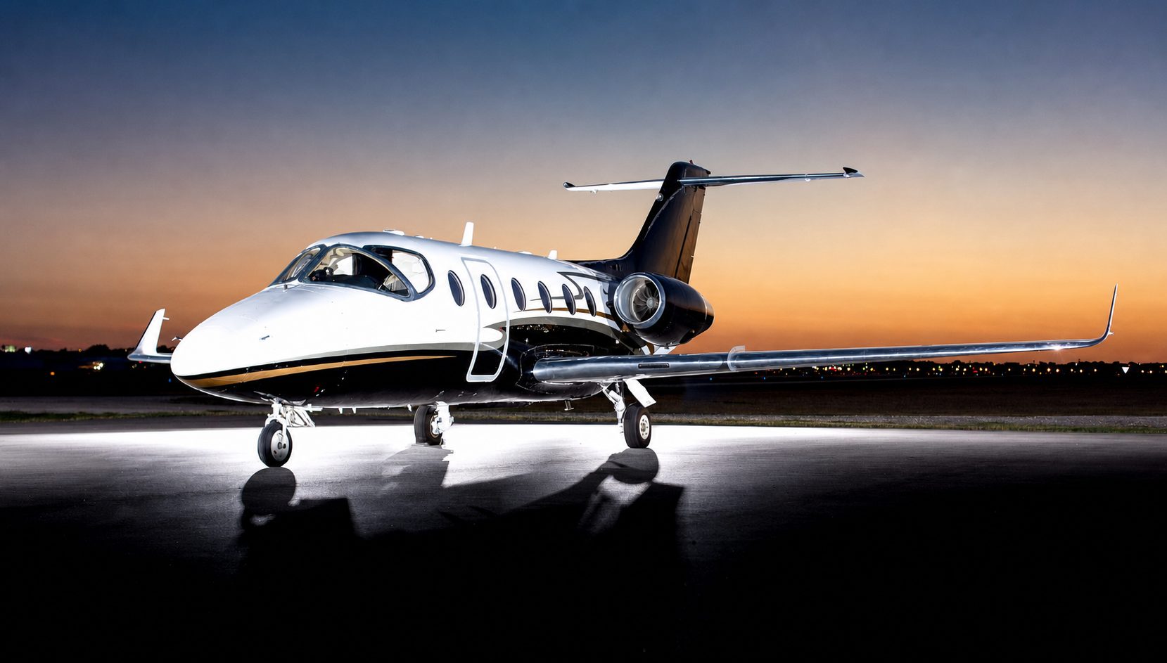 Black and white Hawker 400XPR parked on an airport apron at sunset