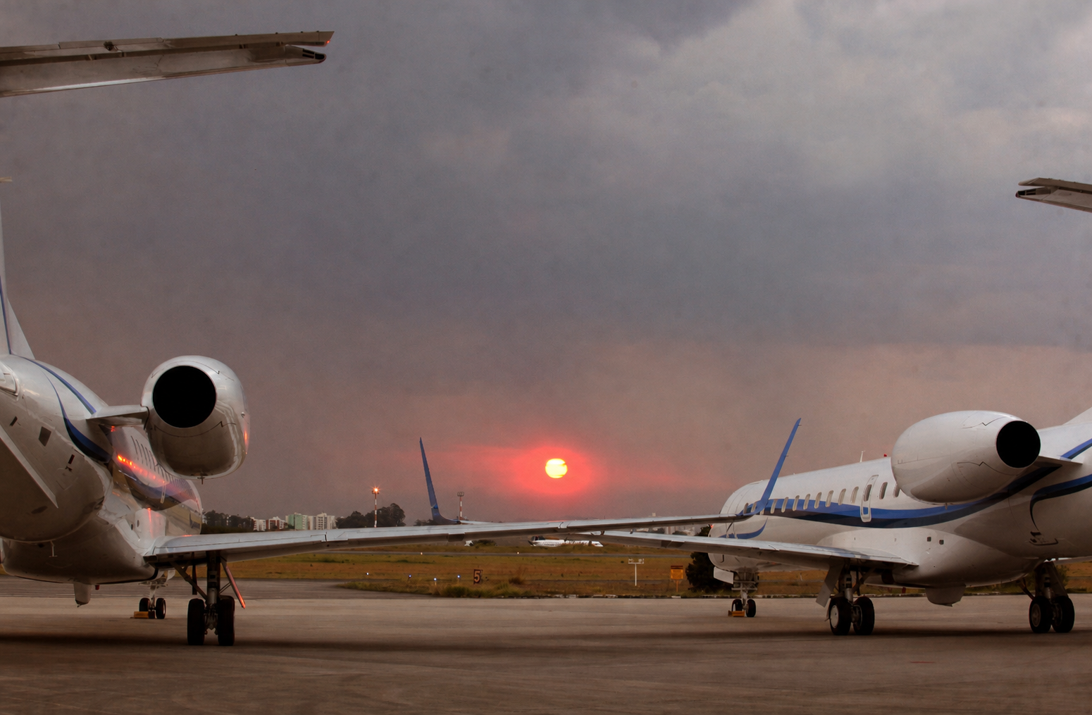 Two business jets on an airport ramp at sunset