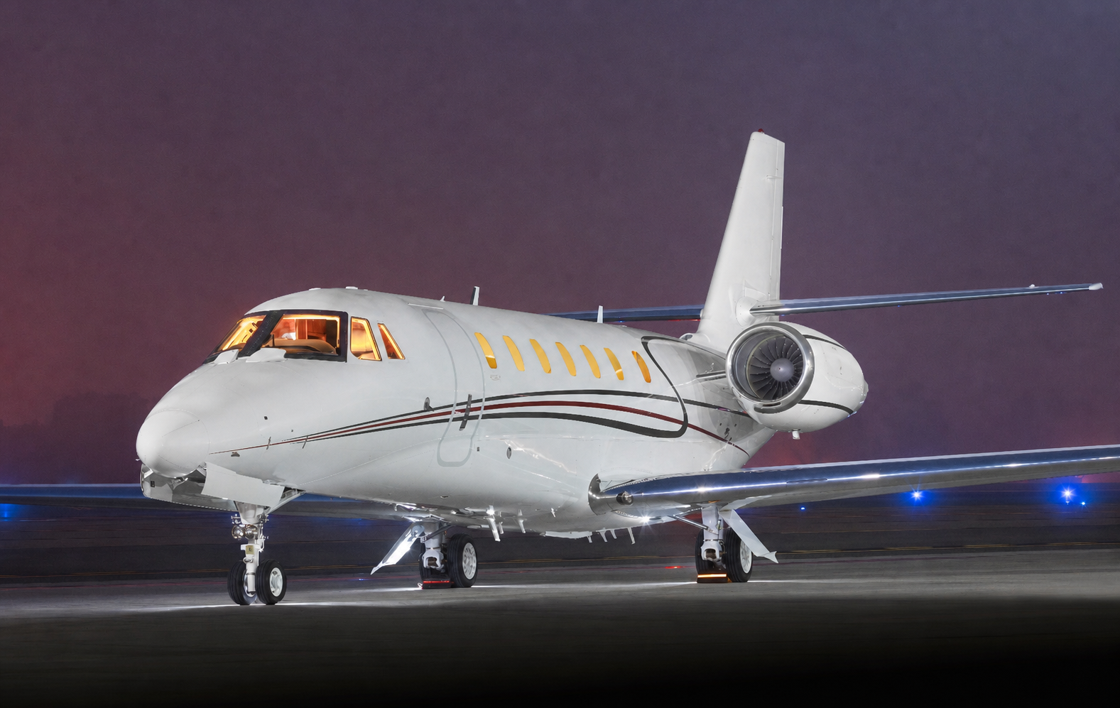 White business jet illuminated on an airport ramp at night
